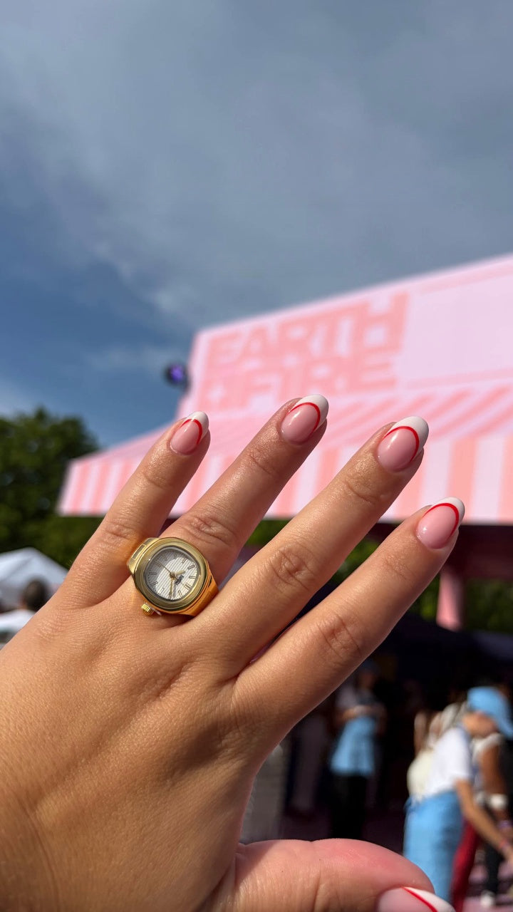 Client wearing a gold EARTH PLUS FIRE watch ring with a light watch face